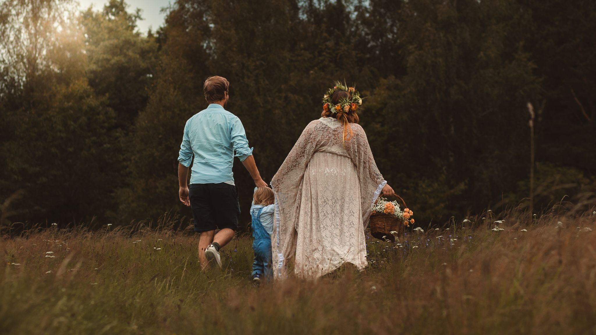 Familj som går hand i hand på en blomsteräng i solnedgång