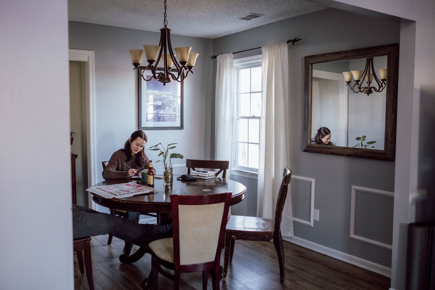 woman sitting at kitchen table alone writing wedding vows in a notebook in virginia beach home