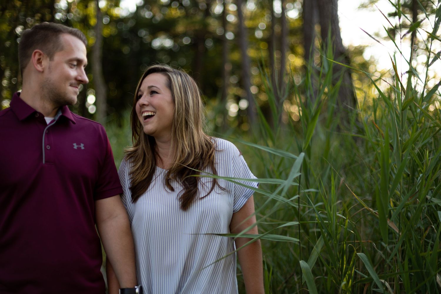 Joyful couple laughing together during outdoor photo session in nature.