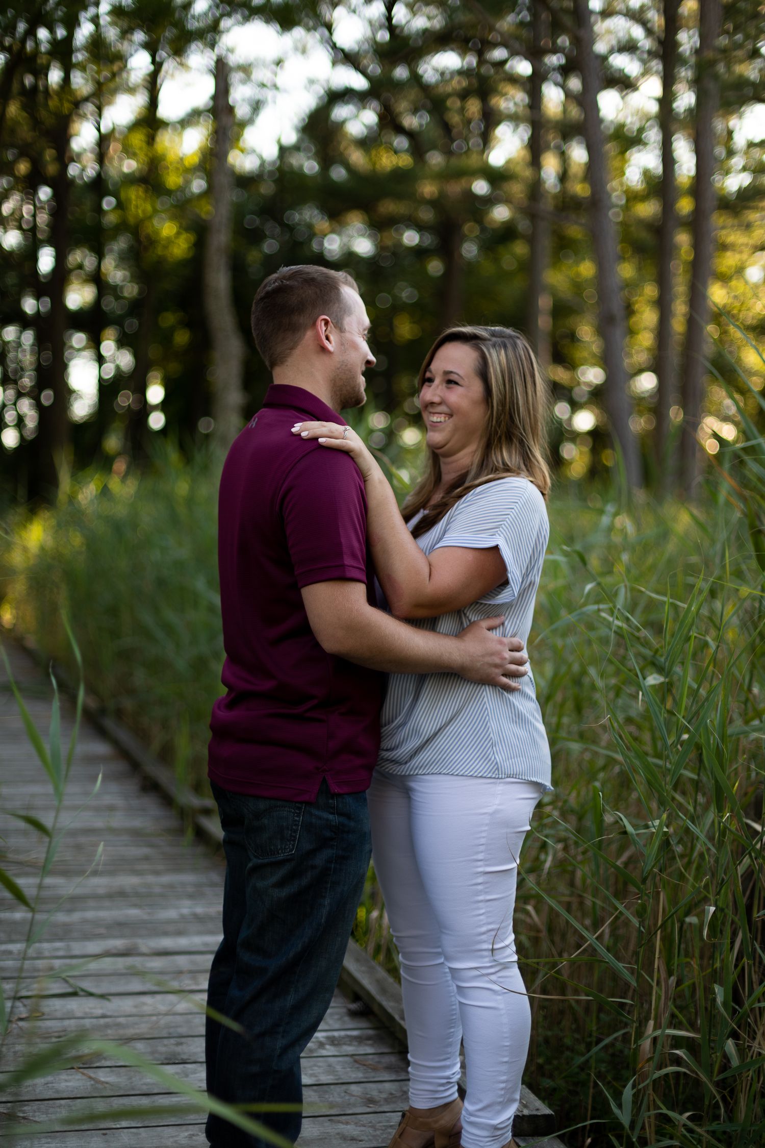 Couple shares loving moment on wooden boardwalk surrounded by natural greenery.