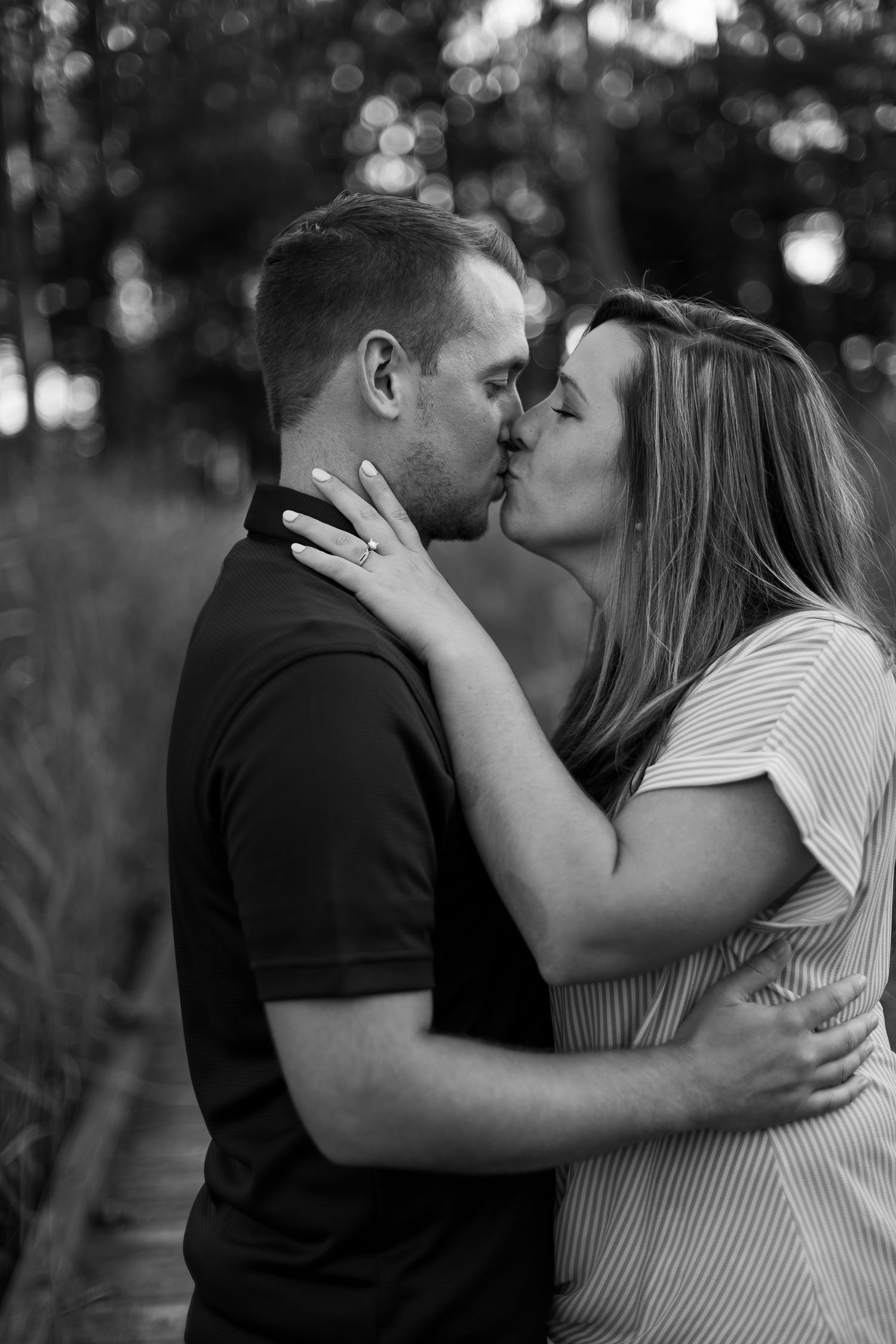 Intimate black and white portrait of couple sharing romantic moment on nature path.