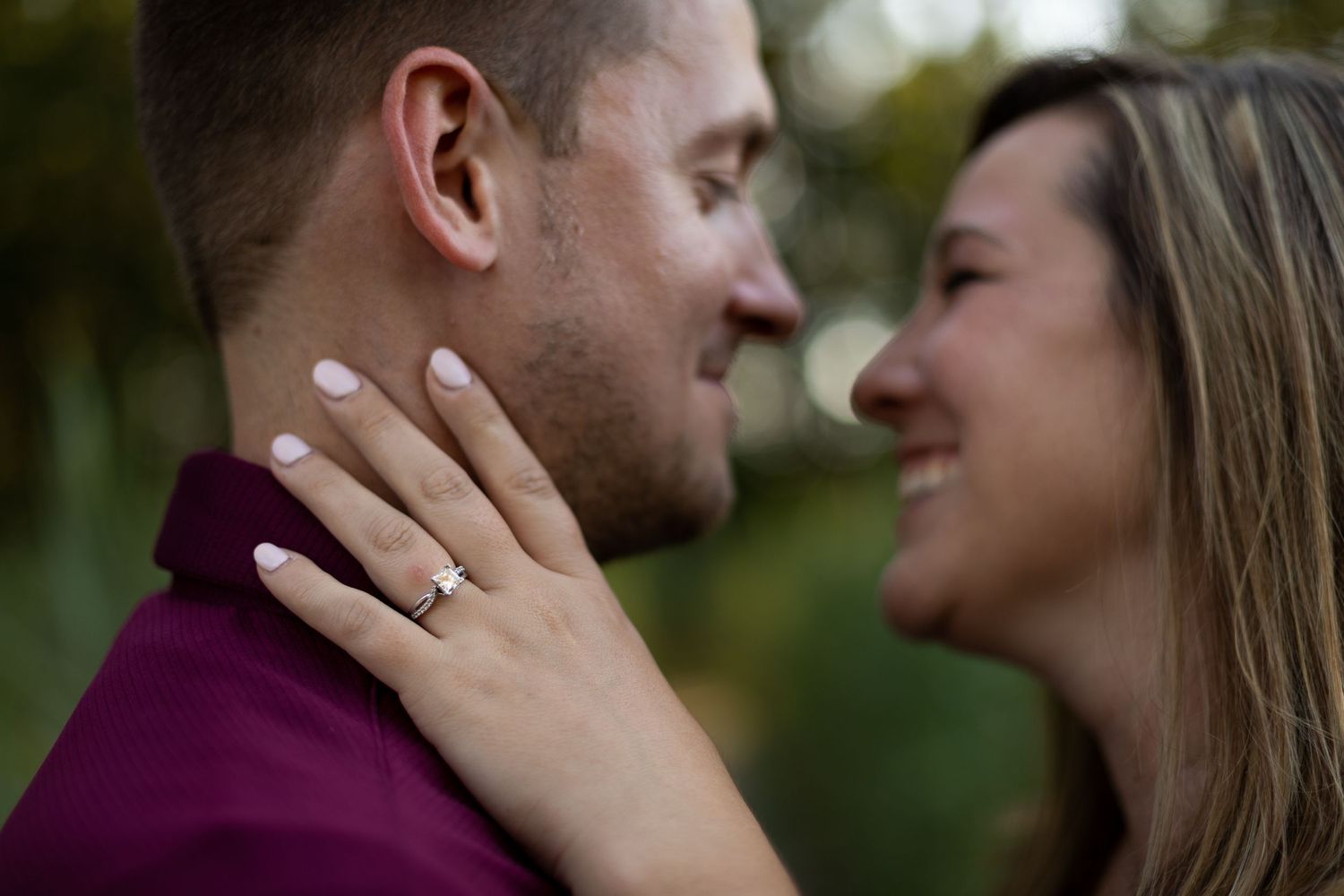 Close up of engagement ring as couple shares intimate moment outdoors.