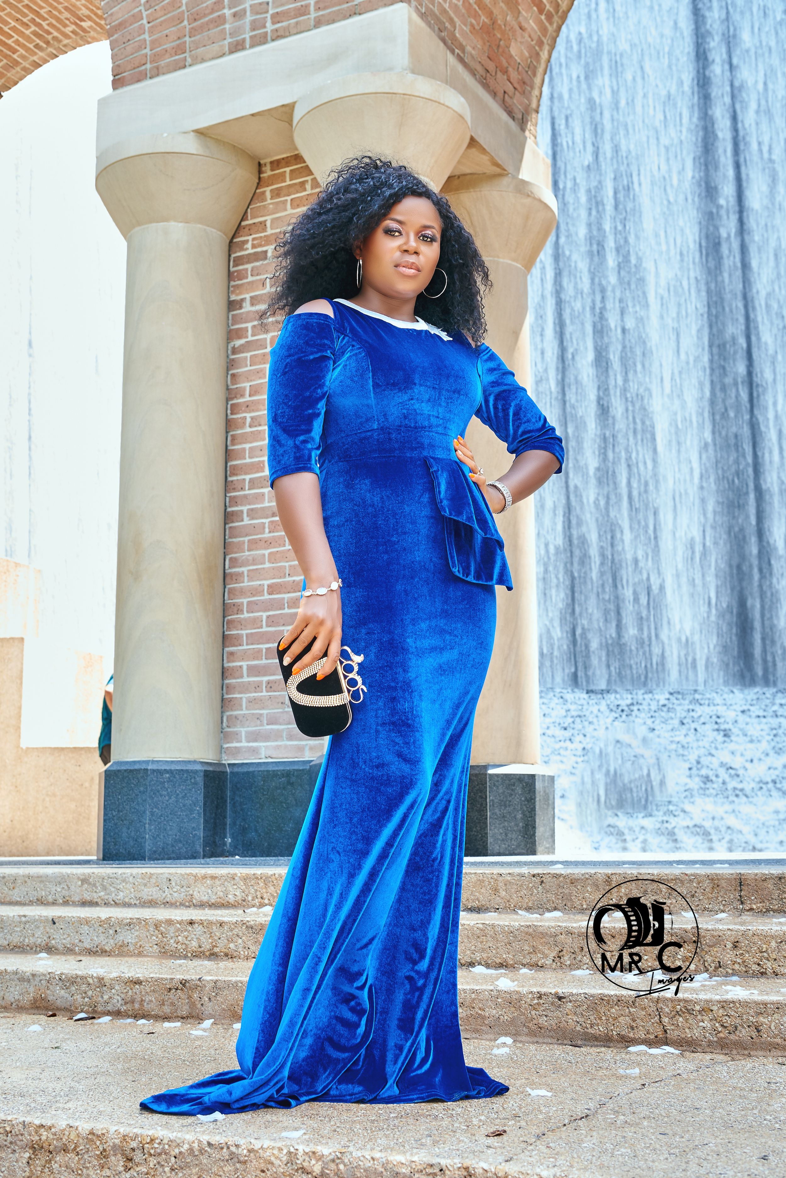 Long blue velvet gown photographed near classical columns and a water feature.