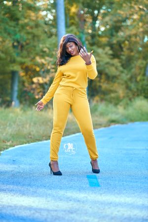 Dynamic pose in bright yellow activewear set against natural outdoor backdrop.