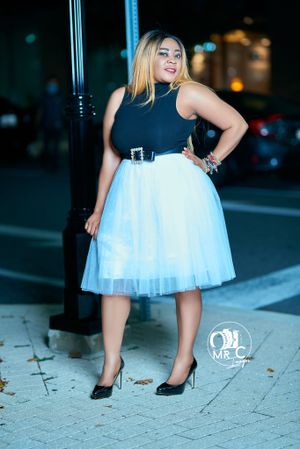 Stylish outfit featuring black top and white tulle skirt in urban setting at night.
