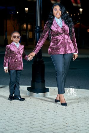 Matching velvet burgundy blazers worn by adult and child in nighttime urban setting.