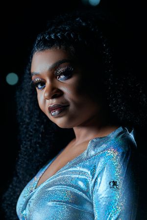 Close-up portrait showing sparkling makeup and a shimmering blue evening dress.