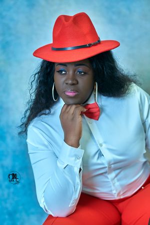Stylish red fedora and white shirt combination against a blue studio backdrop.