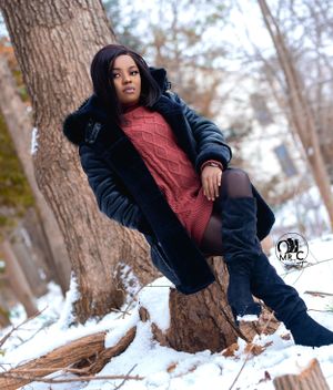 Winter fashion portrait featuring a cozy black coat and red sweater against a snowy tree backdrop.