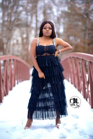A navy blue tiered tulle dress styled on a snow-covered bridge creates a romantic winter scene.