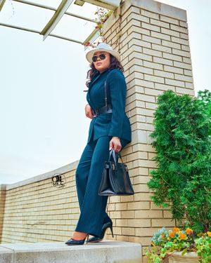 Professional navy suit ensemble with hat and handbag photographed on brick steps outdoors.