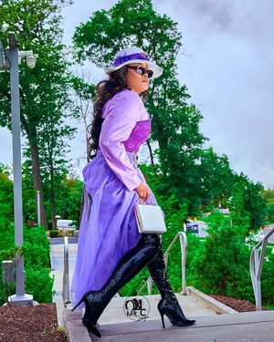 Purple vintage-inspired dress with matching hat and boots in outdoor setting.