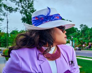 Elegant summer style with white hat adorned with blue ribbon and lavender blazer outdoors.