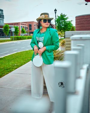 Fashion-forward outfit with green blazer, white pants and stylish accessories in an urban setting.