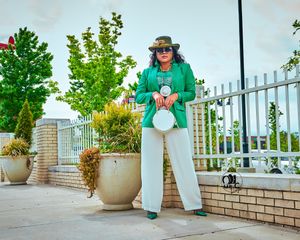 Chic green blazer paired with white pants and fashionable accessories in urban setting.