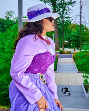 Stylish purple ensemble with matching hat and sunglasses in an outdoor setting.