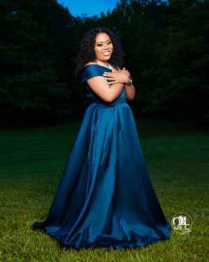 Stunning off-shoulder royal blue ball gown photographed in an outdoor evening setting.
