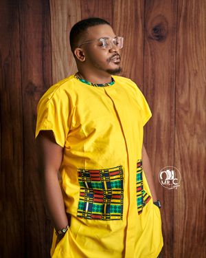 A modern yellow outfit with African print pocket detail styled against wooden wall backdrop.