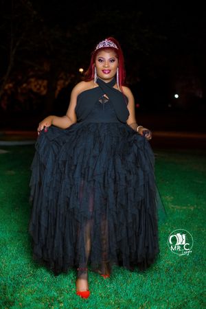 An elegant evening portrait featuring a black tulle gown and tiara against nighttime greenery.