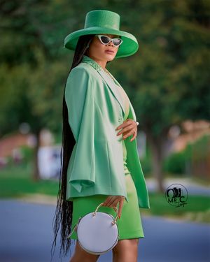 Fashion forward mint green ensemble with matching hat, white circular bag, and retro sunglasses.