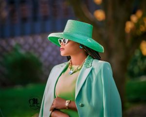 Stylish mint green blazer ensemble with matching wide-brimmed hat and statement jewelry.