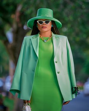 Monochromatic green outfit featuring a structured blazer, matching hat, and white-rimmed sunglasses.