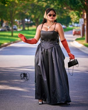 Elegant black ball gown styled with red opera gloves and statement accessories on a suburban street.