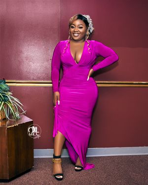 A glamorous evening look featuring a form-fitting magenta gown with long sleeves and a deep v-neckline.