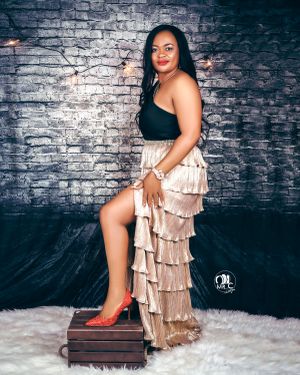 Glamour shot with tiered champagne skirt against textured brick wall backdrop.