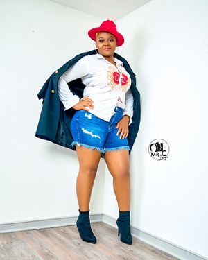Stylish outfit with red hat, white top, and denim shorts against white wall.