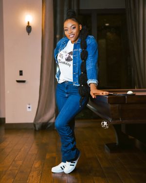 Casual denim on denim outfit pose against wooden floor interior.