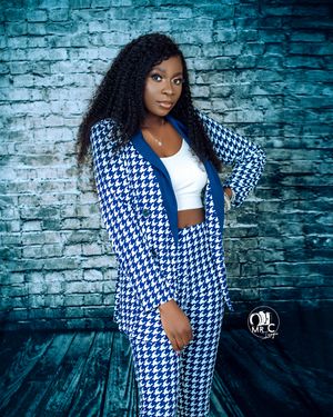 Fashion portrait with houndstooth print suit against textured blue brick wall background.