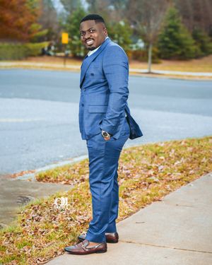 Professional outdoor portrait featuring a person in a tailored blue suit standing on a sidewalk in autumn.