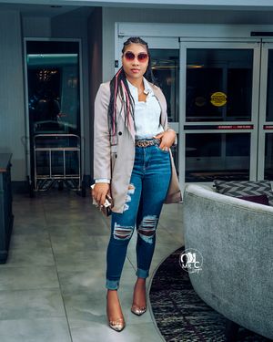 Street style photo in beige blazer and ripped jeans with modern interior background.