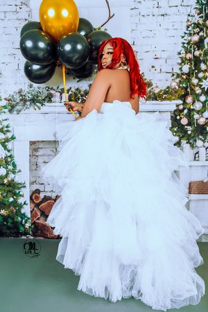A dramatic bridal photo showing the back of a white tulle dress with balloons and Christmas decor.