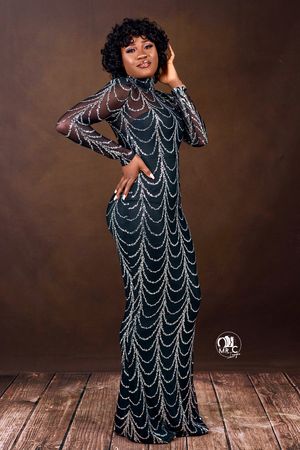 Elegant evening gown with intricate silver beaded pattern against dark backdrop.
