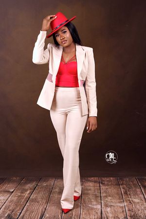 Stylish outfit featuring red hat, cream suit and red accents in studio setting.