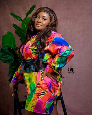 Vibrant fashion photo showcasing a colorful patterned dress with bold rainbow hues against pink background.