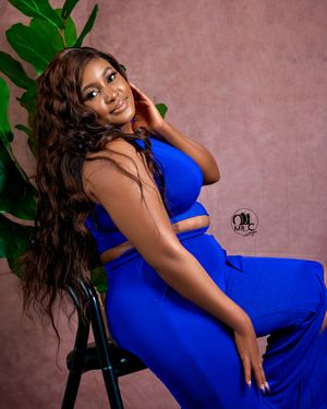 Stylish portrait featuring a blue two-piece outfit against a pink backdrop with green plant accents.