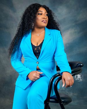Professional portrait in bright turquoise blazer suit against dramatic cloudy backdrop.