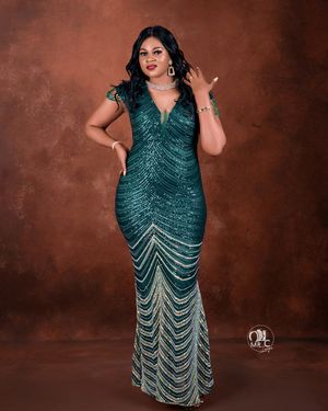 A stunning emerald green sequined gown with v-neck and mermaid silhouette against brown backdrop.