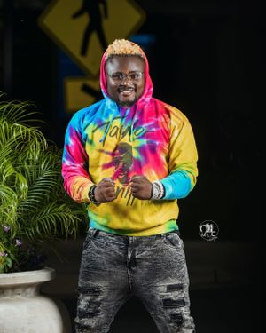 Casual portrait in tie-dye rainbow hoodie against dark background with street signs.