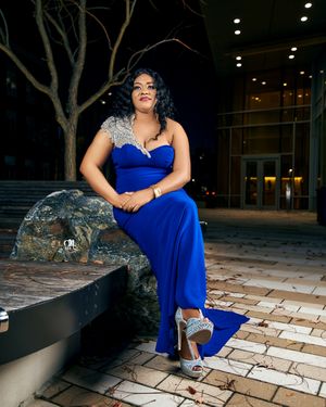 Elegant evening portrait in a royal blue gown with silver accents against an outdoor nighttime backdrop.