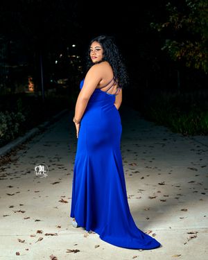 Royal blue form-fitting evening gown with train photographed on path at night.