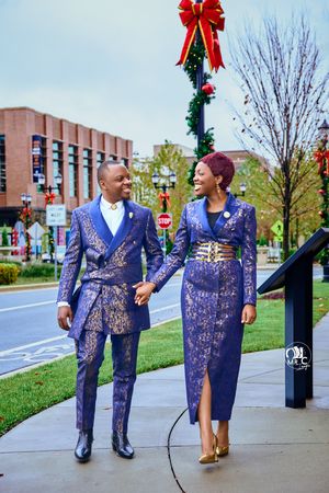 Couple in matching navy and gold formal wear walking beneath holiday decorations.