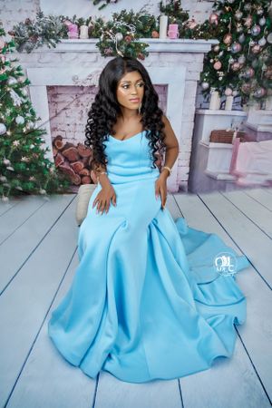 Elegant light blue ballgown with sweetheart neckline photographed against floral backdrop with vintage fireplace.