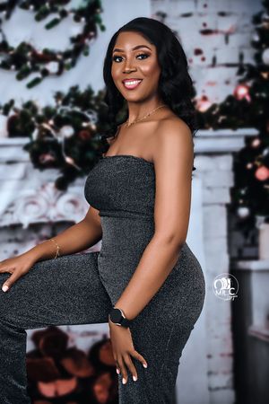 Elegant portrait of someone in a fitted black dress against a decorative holiday backdrop.