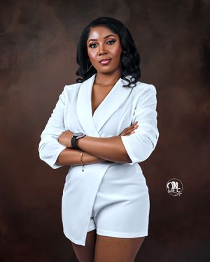 Professional studio portrait featuring a white blazer romper outfit against a dark background.