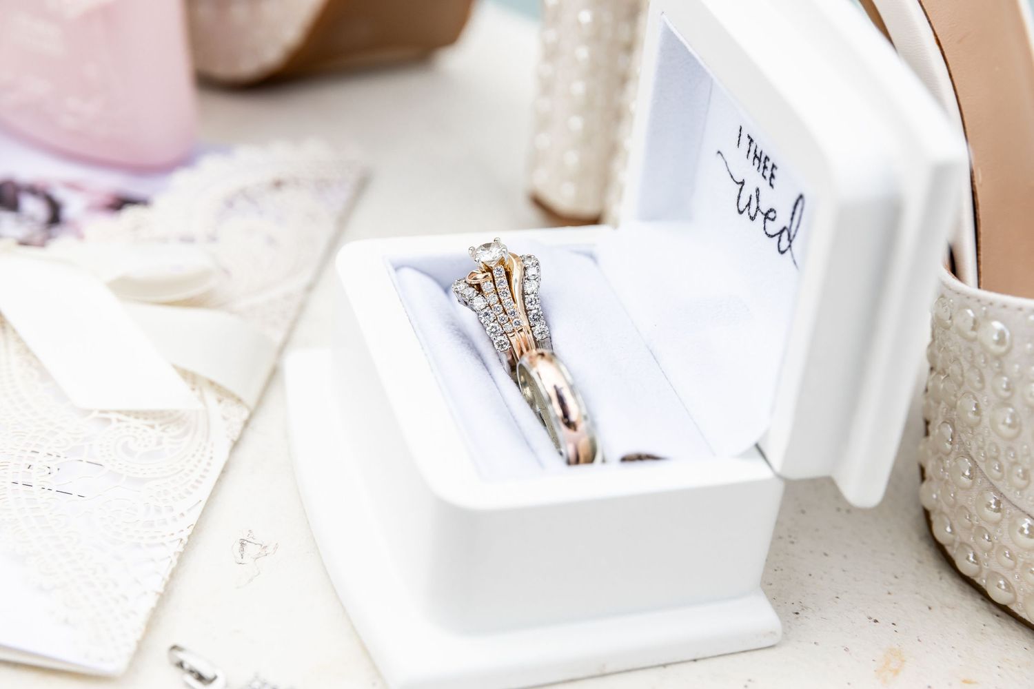 Elegant diamond engagement ring displayed in white ring box with bridal accessories.
