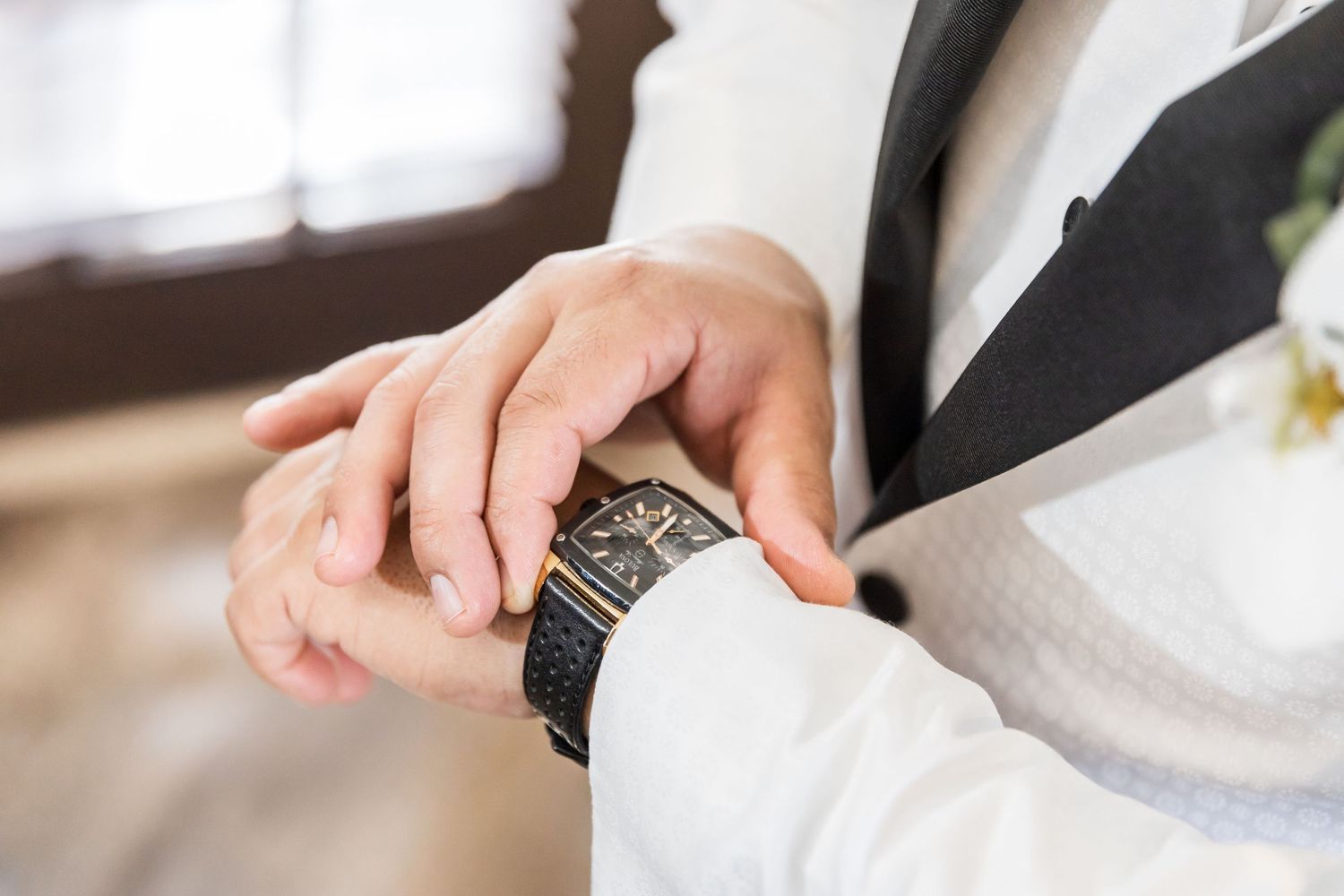 Close-up detail shot of formal watch on wrist with wedding attire.